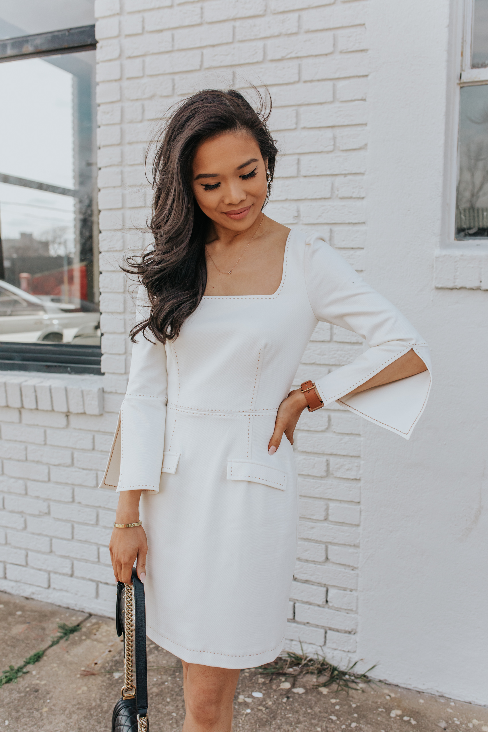 Petite blogger Hoang-Kim wears a white split sleeve dress with olive + piper earrings, Kendra Scott love knot diamond necklace in Bishop Arts District of Dallas