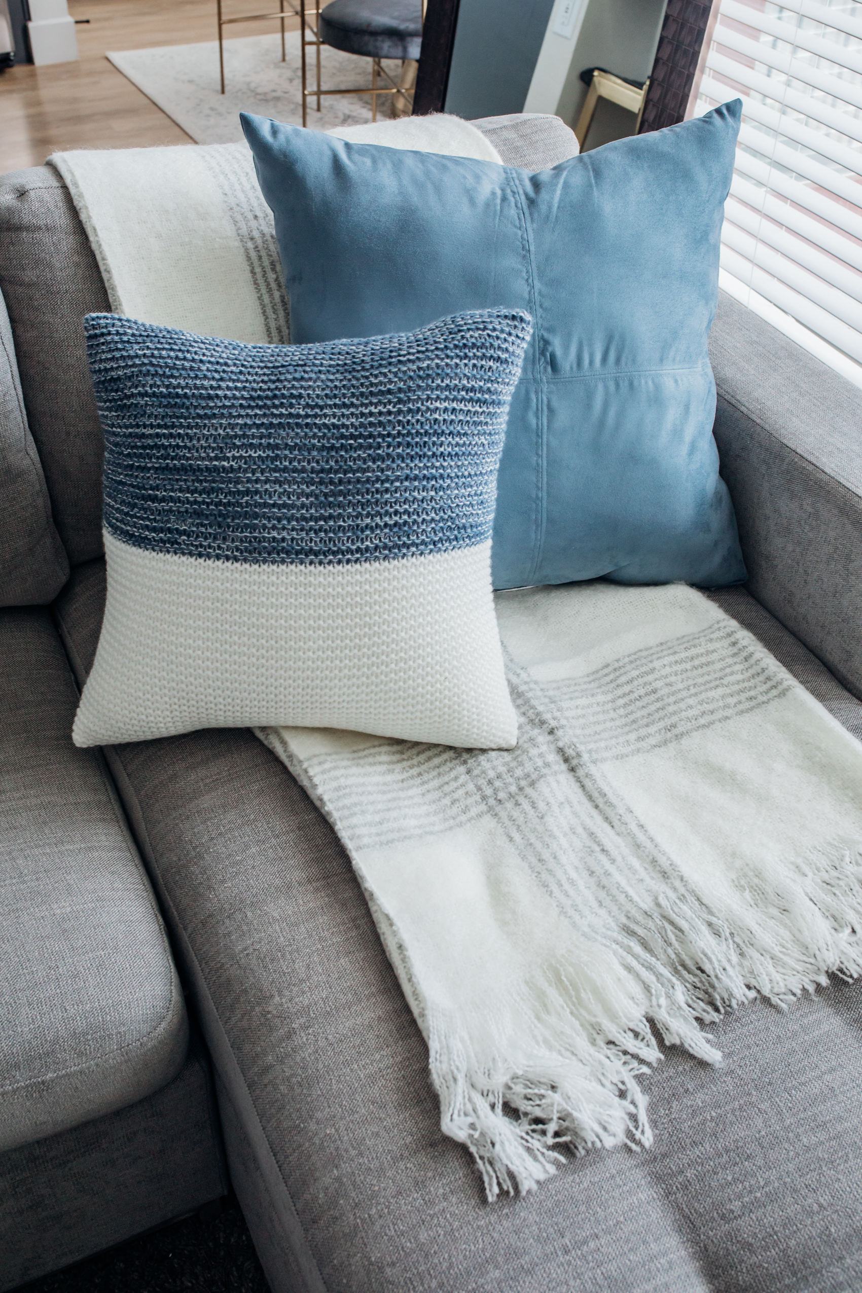 Cozy living room decor with blue and cream throw pillows and a striped throw blanket