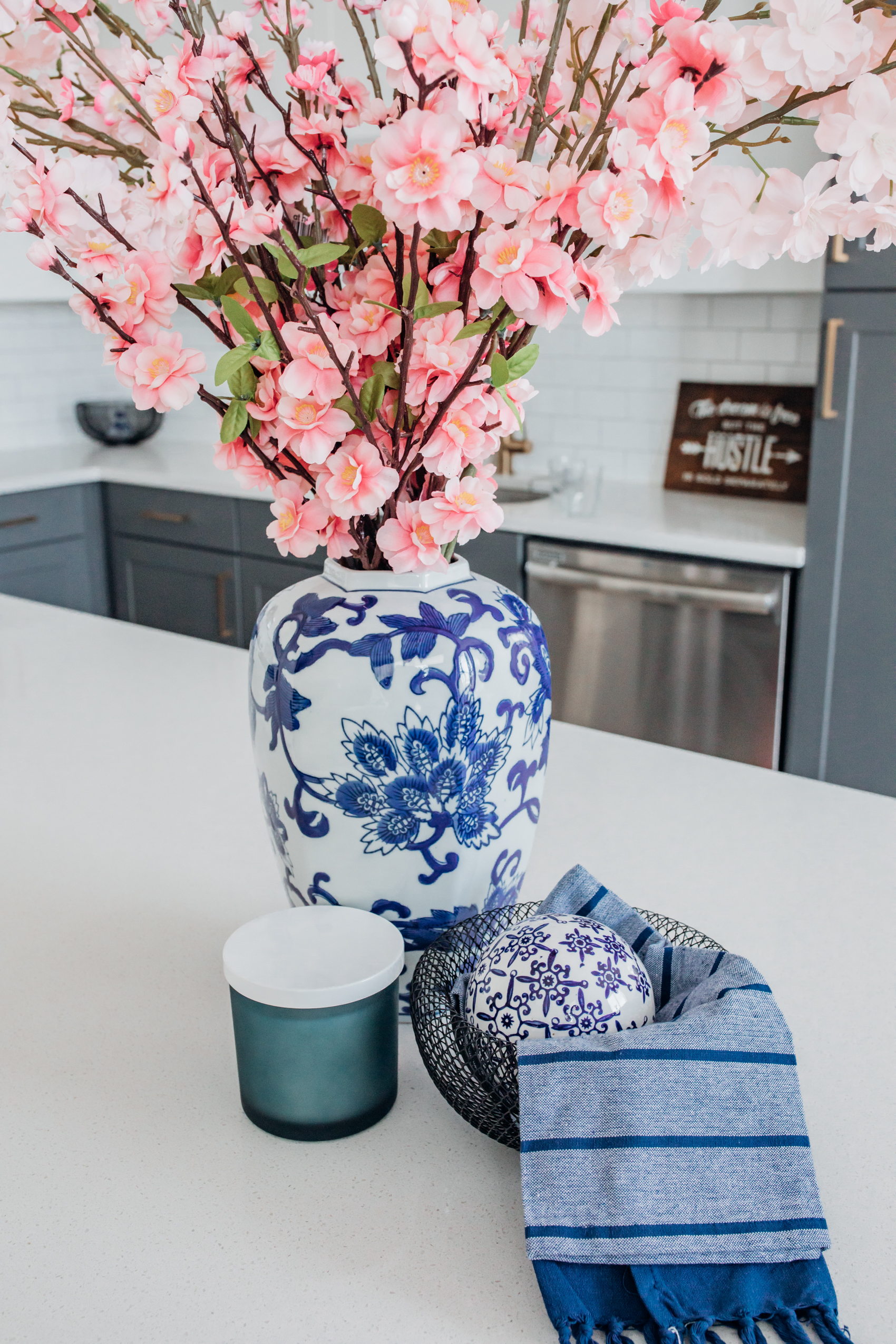 Spring home decor in a two-toned kitchen with a ginger jar, faux cherry blossoms, and black bowls