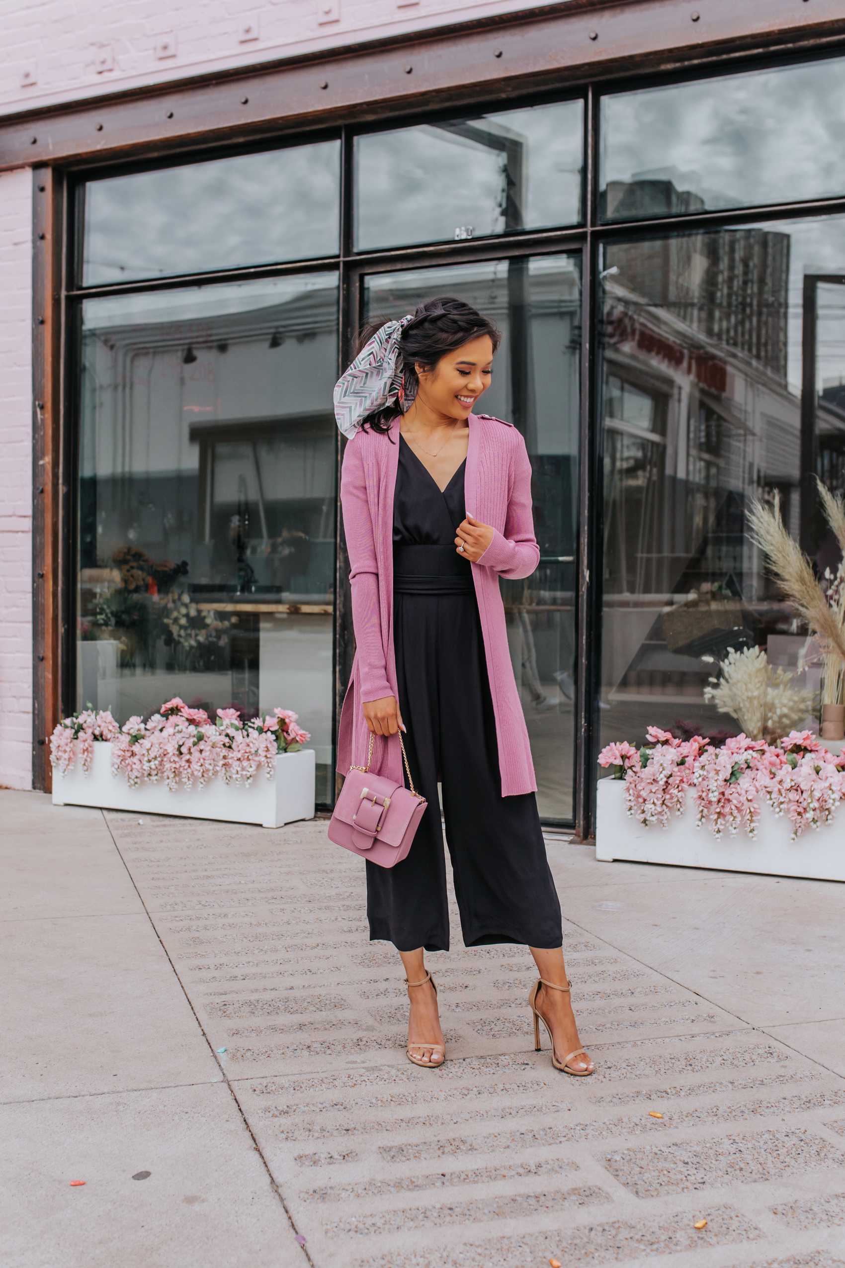 Hoang-Kim styles a spring outfit with a black jumpsuit, pink cardigan, chevron hair scarf, heeled sandals and a pink mini bag