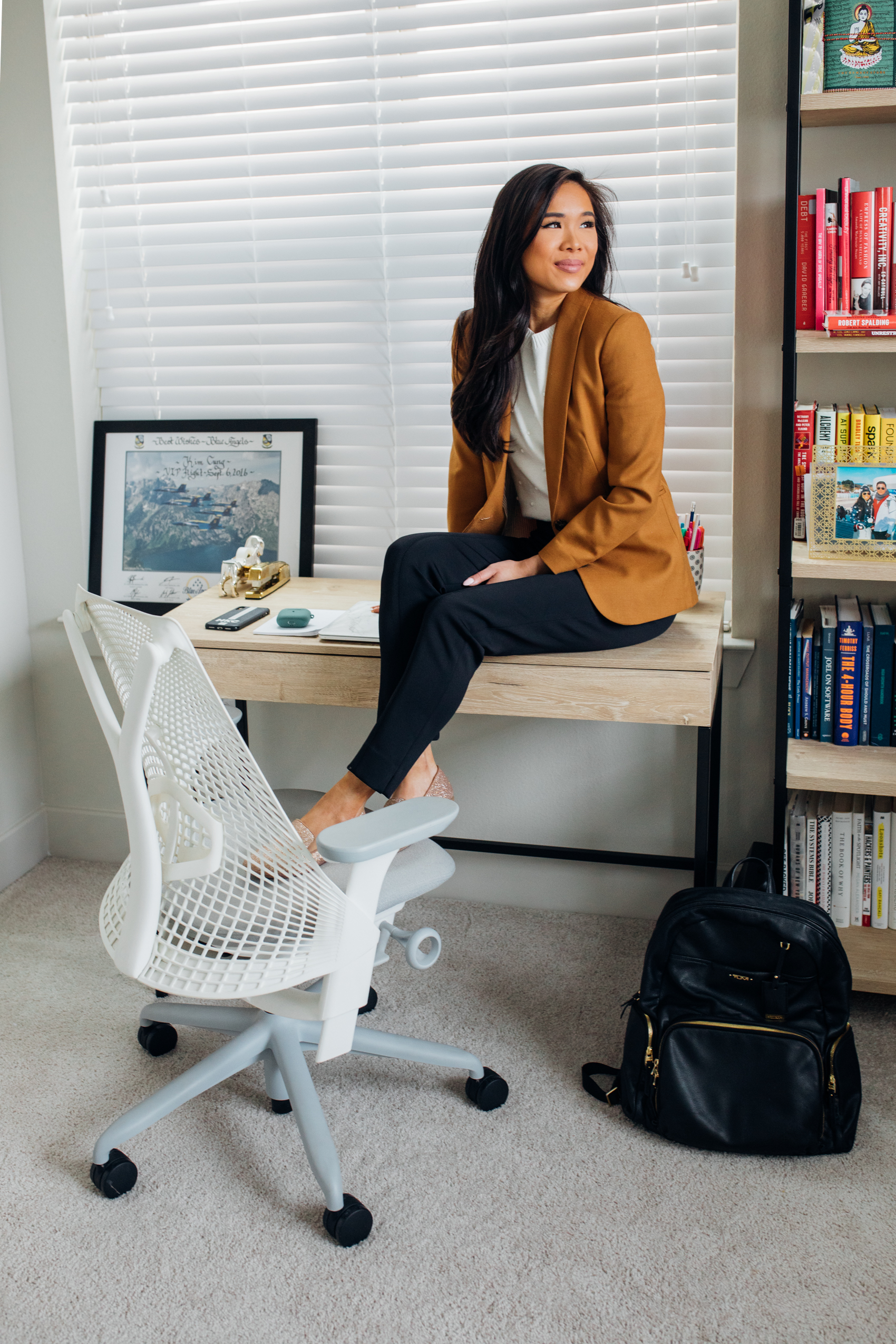 Blogger Hoang-Kim in her Dallas apartment home office with a writing desk, Herman Miller Sayl Chair in white, Tumi leather backpack, wearing J.Crew Parke Blazer, Ann Taylor Popcorn Sweater, M.M. LaFleur Scuba Pants and Birdies flats