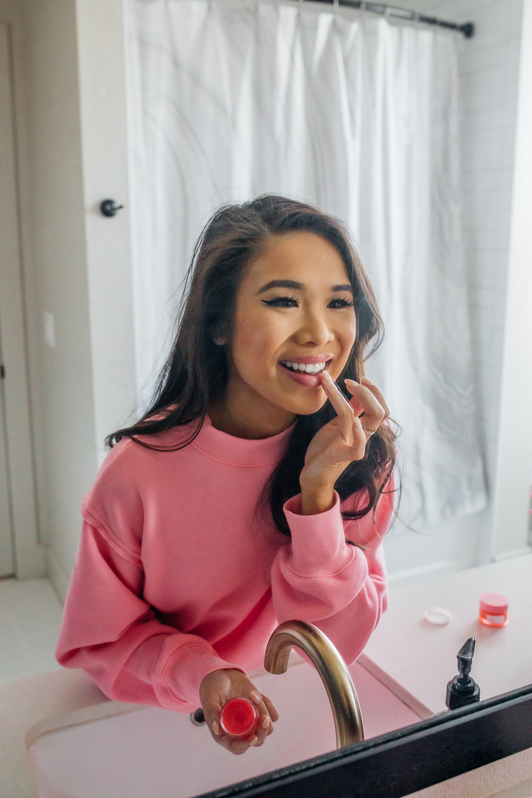 Blogger Hoang-Kim applying Awake Beauty Moisture Balm Daytime Lip Mask in her Dallas apartment master mathroom