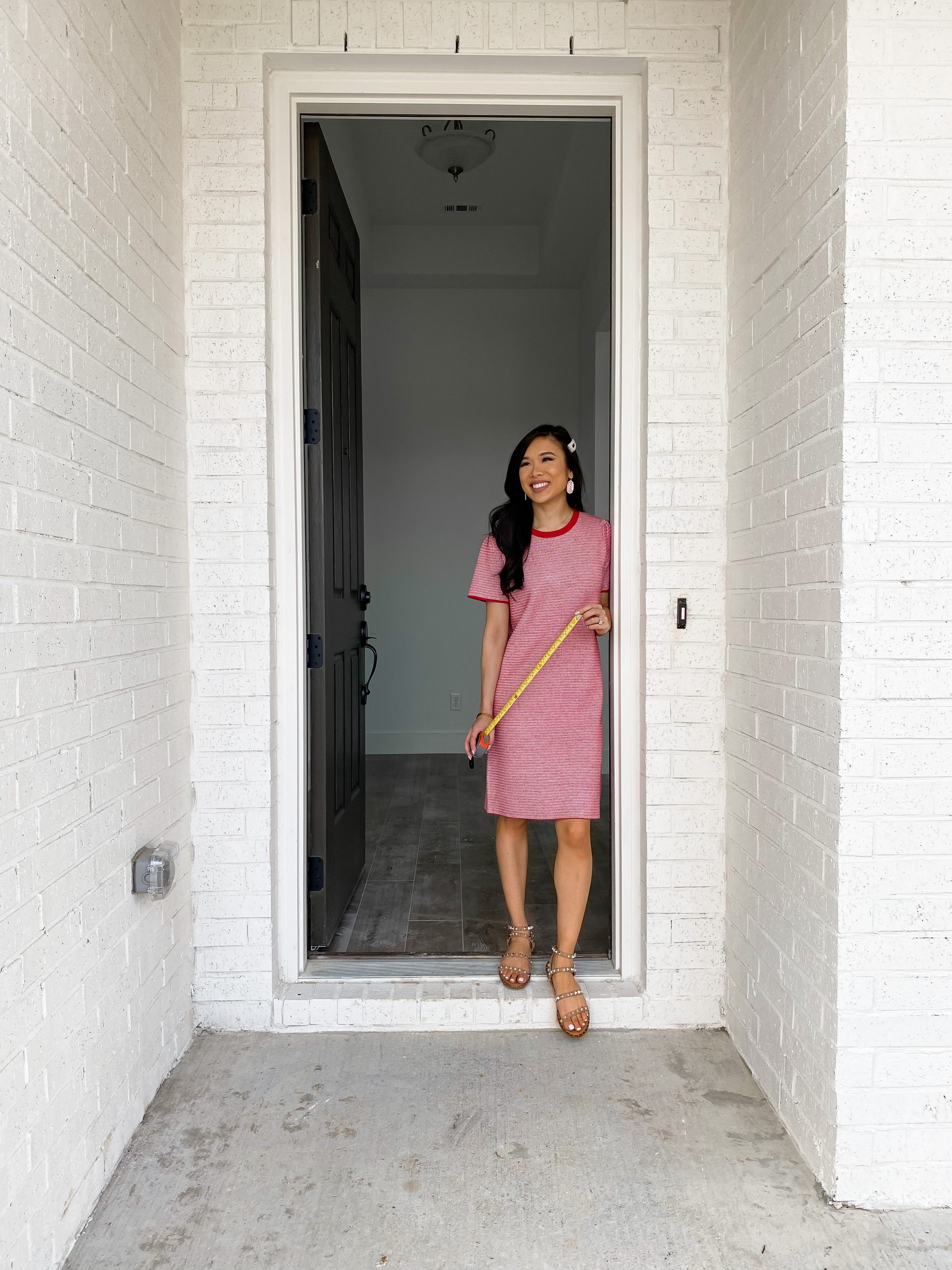 Blogger Hoang-Kim wears a Draper James knit sweater dress with Steve Madden travel sandals outside her new build home in Dallas