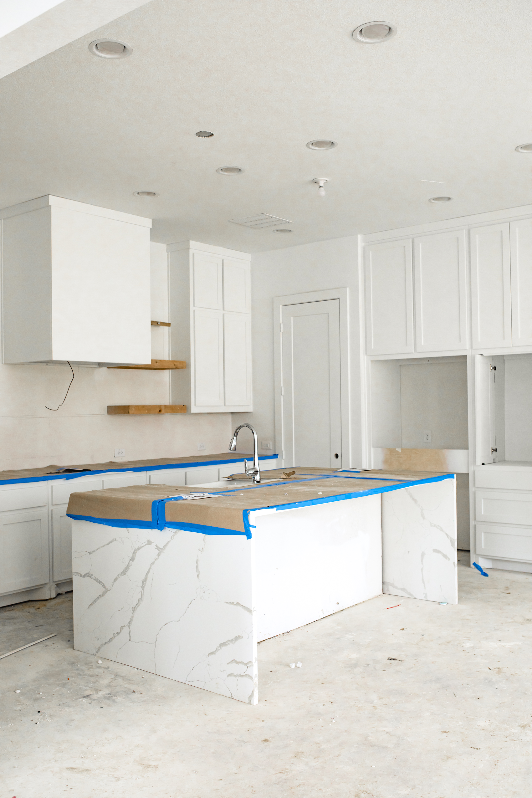 White kitchen with shaker style cabinets, quartz waterfall island and open shelves
