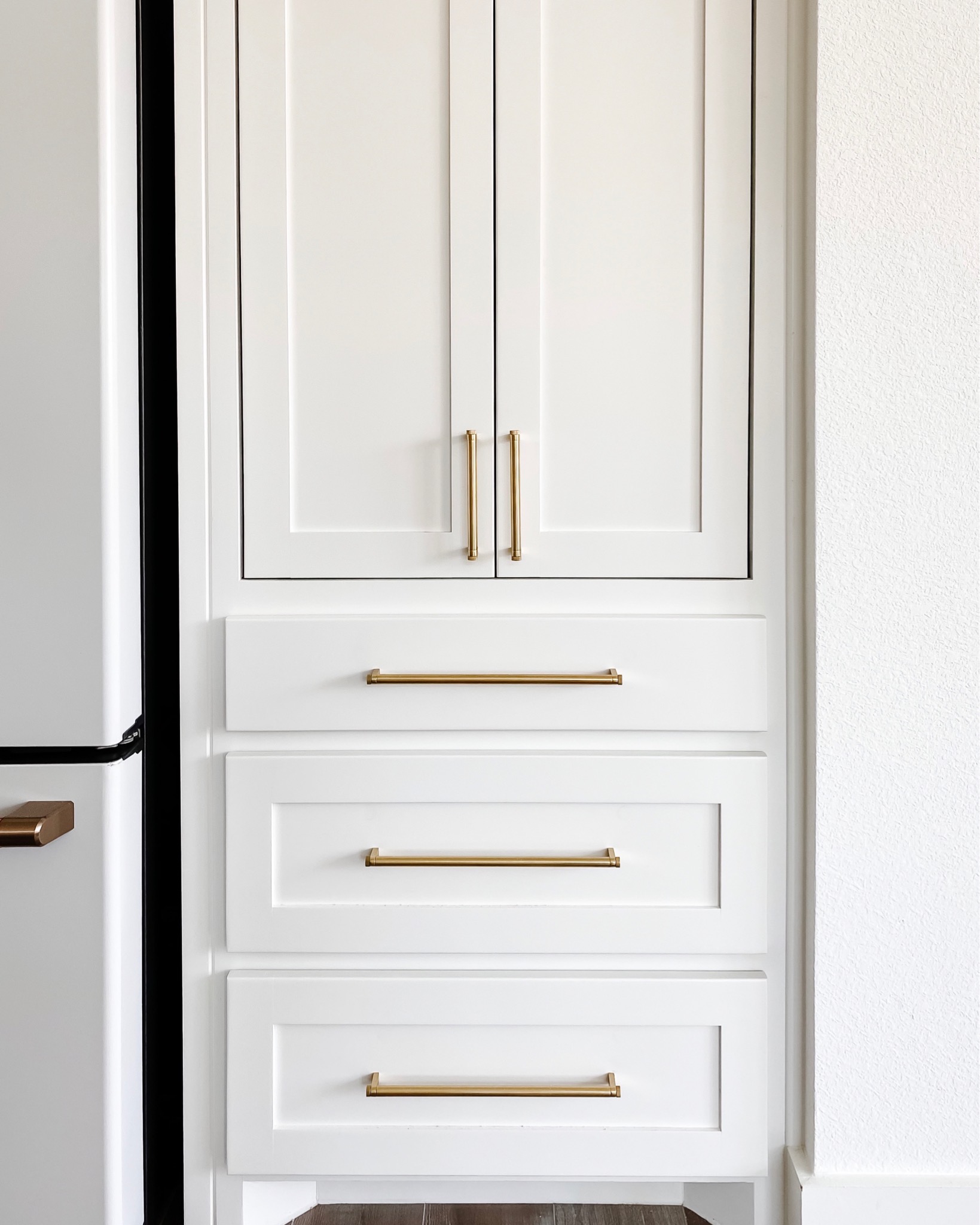 Custom appliance garage with sliding doors, pot and pan drawers and more to hide all those big bulky appliances in a kitchen. Finished with brass Rejuvenation West Slope drawer pulls
