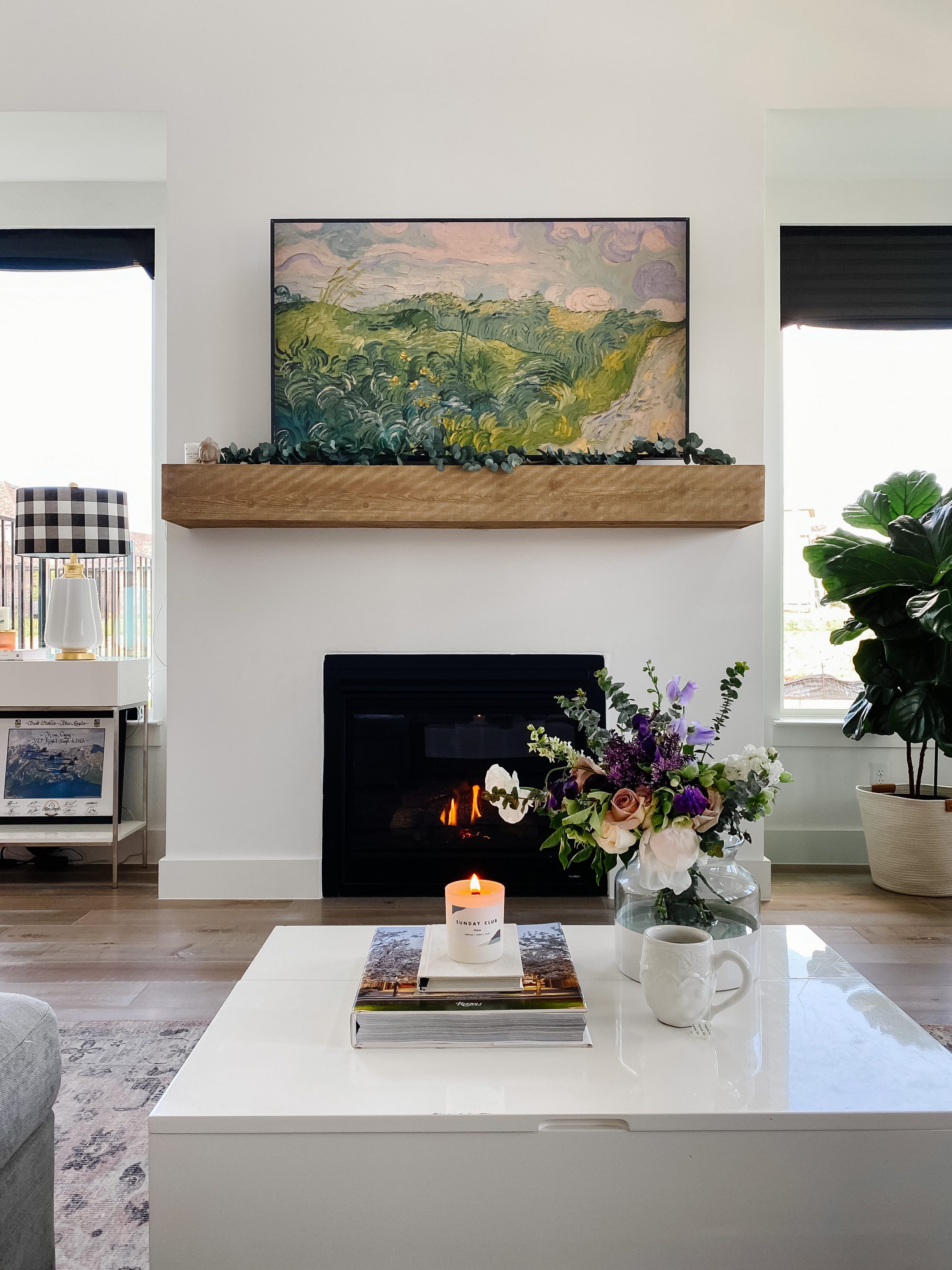 Living room with cedar mantel, Samsung Frame TV, eucalyptus garland, fireplace, fiddle leaf fig plant, lift up storage coffee table and wood wick candle in a new build home in Dallas