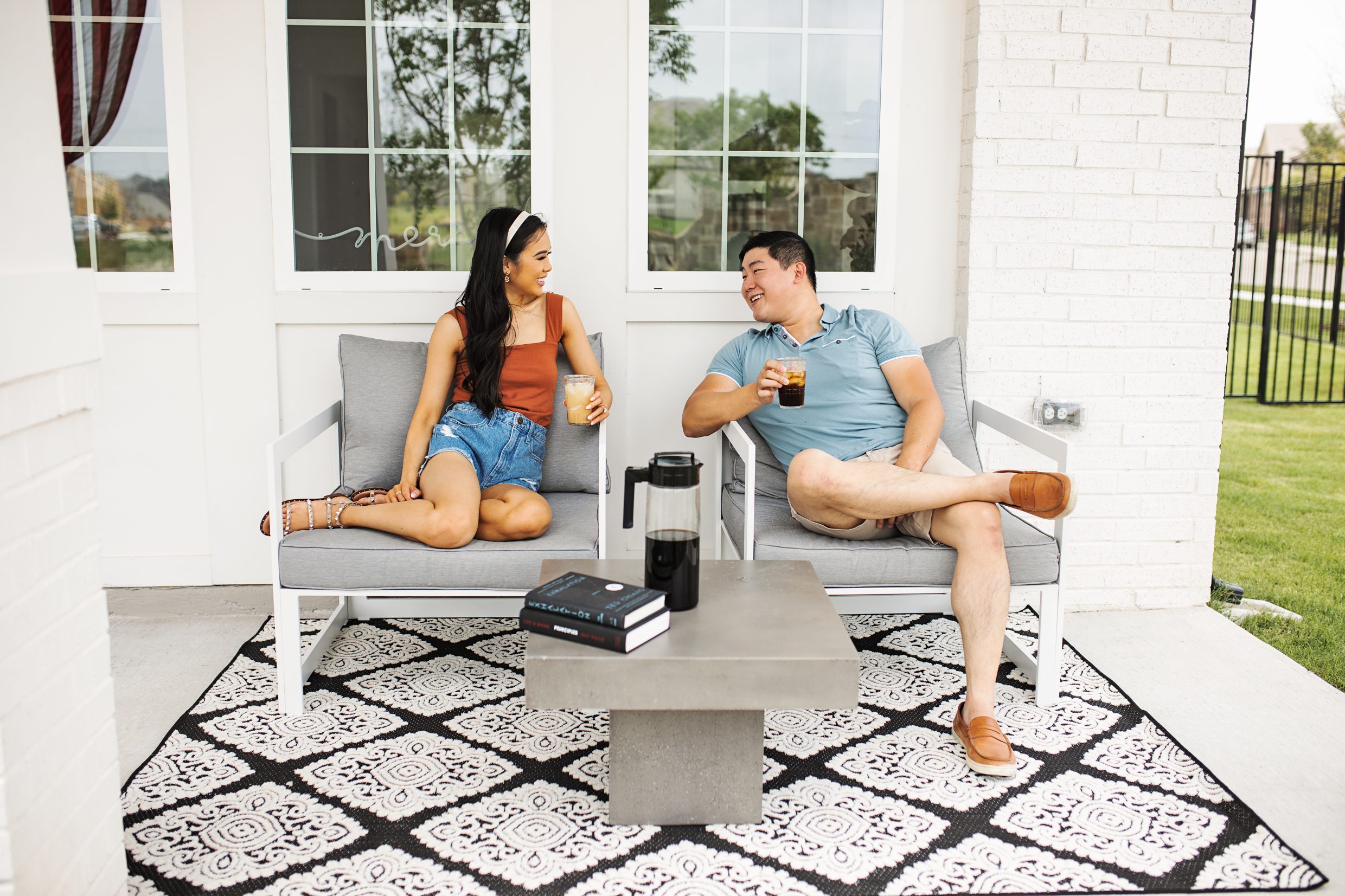 Blogger Hoang-Kim and fiance Jonathan sipping cold brew on their Modern Outdoor Patio furniture from Bed Bath and Beyond with concrete coffee table and black and white rug