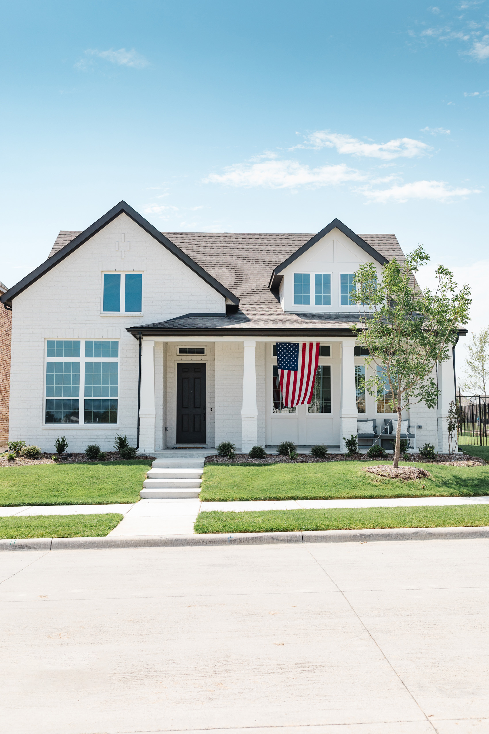 Dallas one-story home with white painted brick in toque white with an American flag on the front