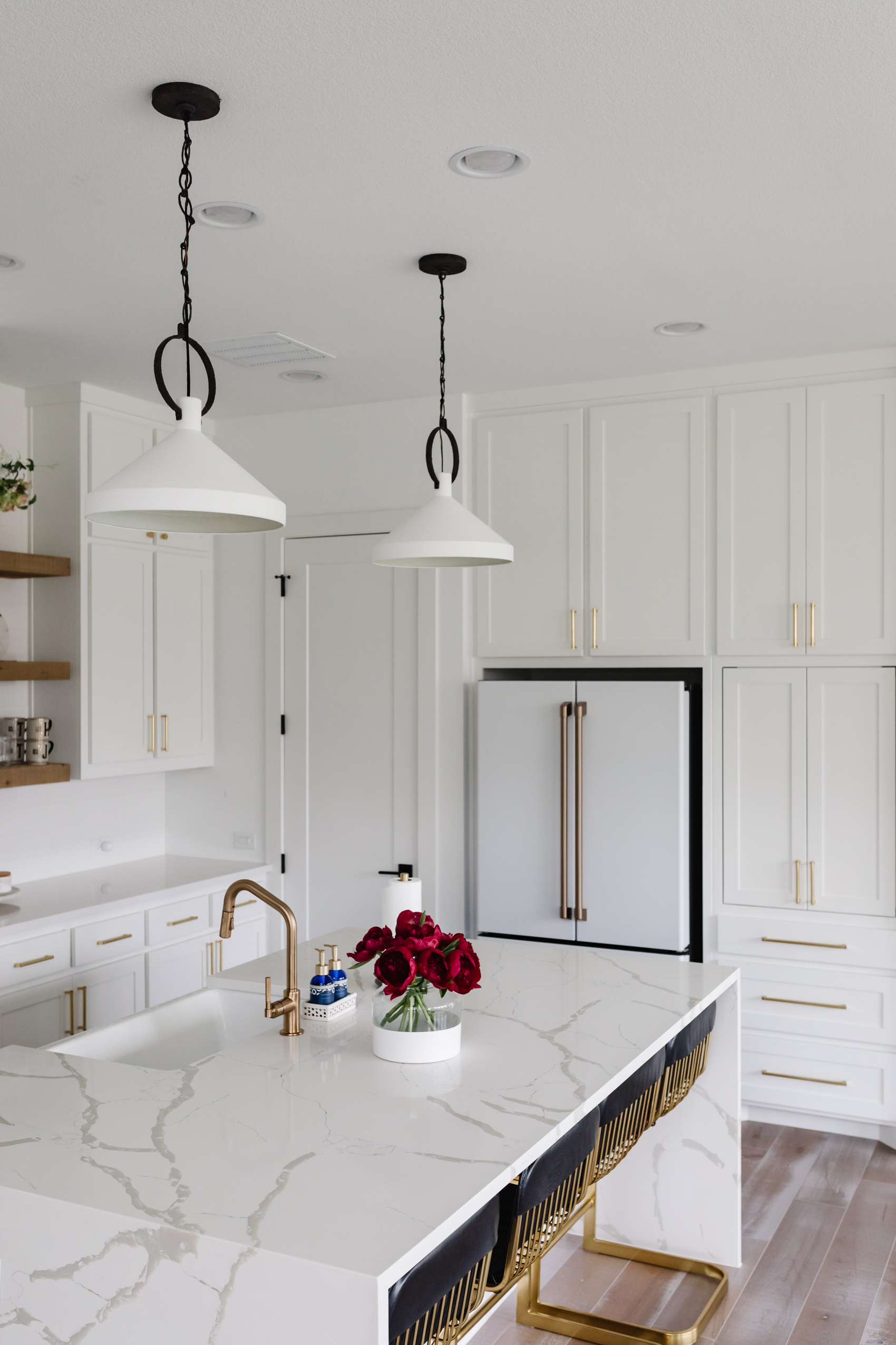 White Black and Brass transitional kitchen with white and black kitchen pendants, calacatta foresta quartz waterfall island and brizo faucet