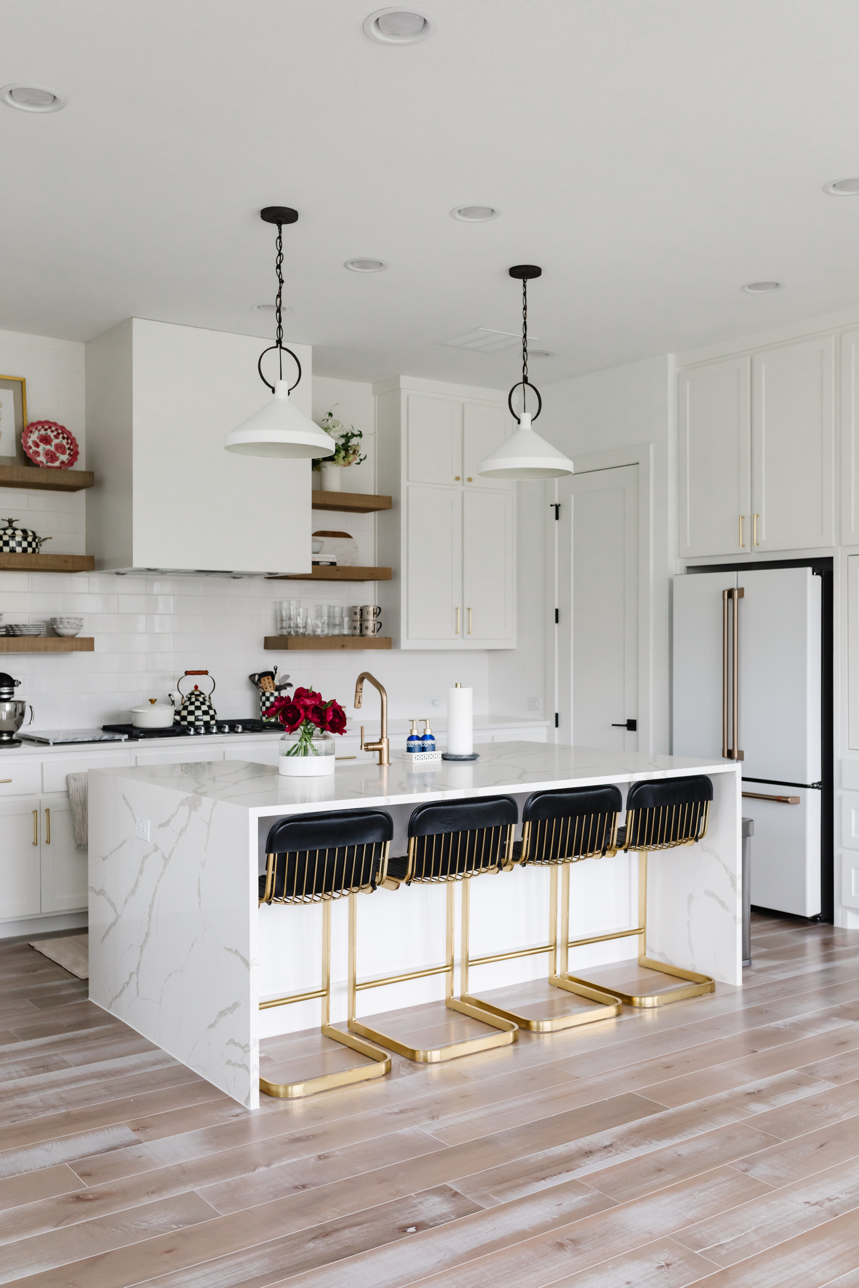Transitional kitchen with quartz waterfall island, brass Brizo faucet, McGee & Co Pendant lights, CB2 Barstools, Cafe Appliances Refrigerator, Rejuvenation West Slope hardware, MacKenzie-Childs utensil holder kettle and more