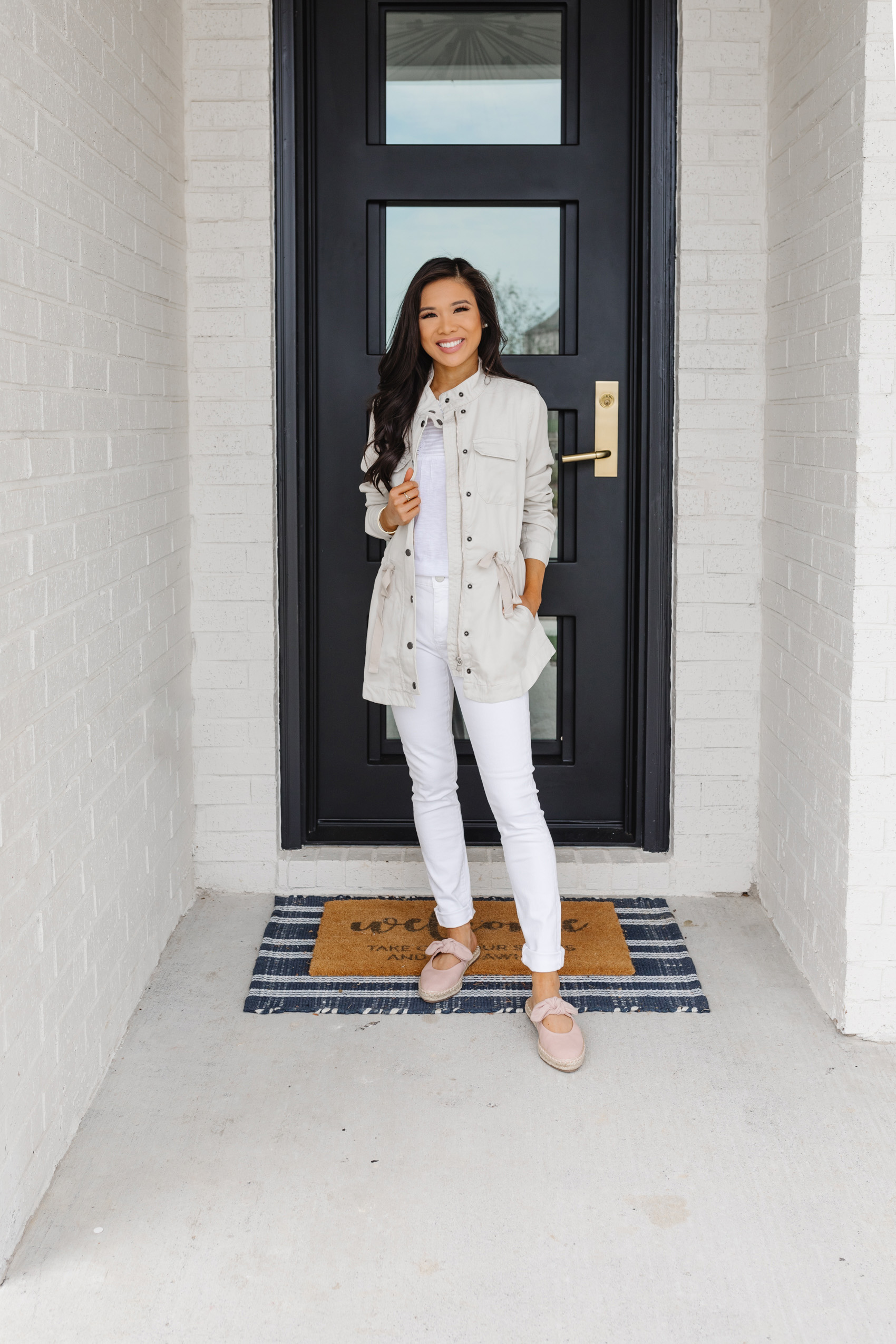 Petite blogger Hoang-Kim wears a cream colored utility jacket with white jeans and pale pink espadrilles