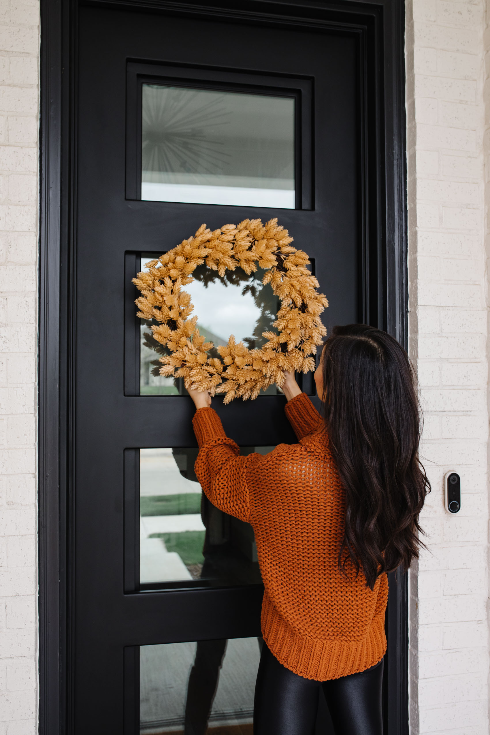 Blogger Hoang-Kim hanging a fall Target wreath on her iron front door outside her Dallas home