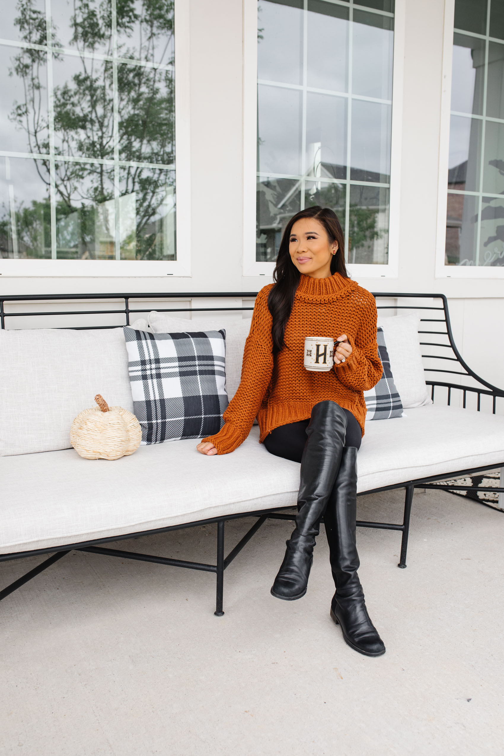 Blogger Hoang-Kim wearing a free people my only sunshine sweater, stuart weitzman 5050 over the knee boots, on her CB2 breton sofa with plaid pillows and anthropologie monogram mug