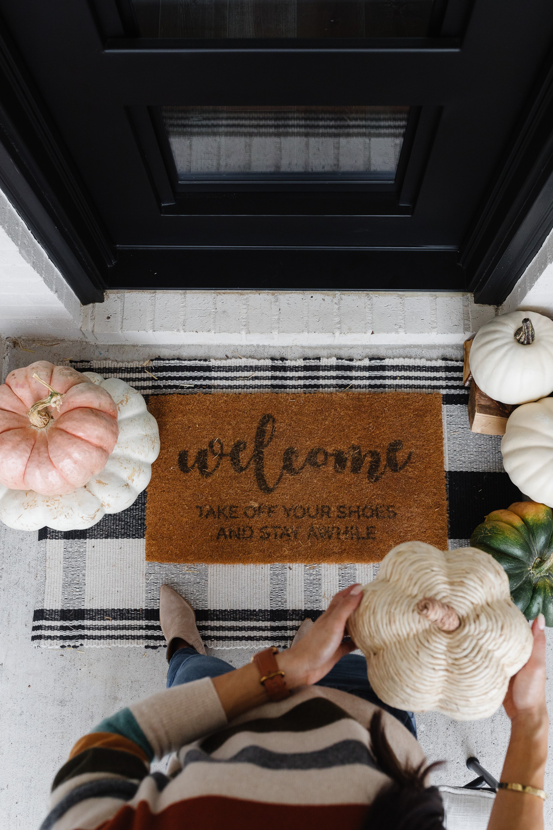 Fall front porch decor with faux and real pumpkins, plaid rug, doormat to remind guests to take off their shoes and iron front door