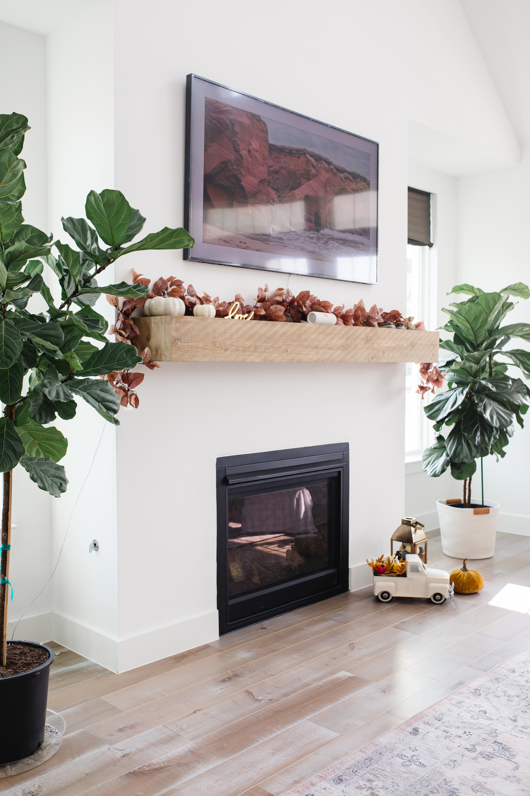 Fall living room decor with a fireplace, burgundy leaves garland, white farmhouse truck and more