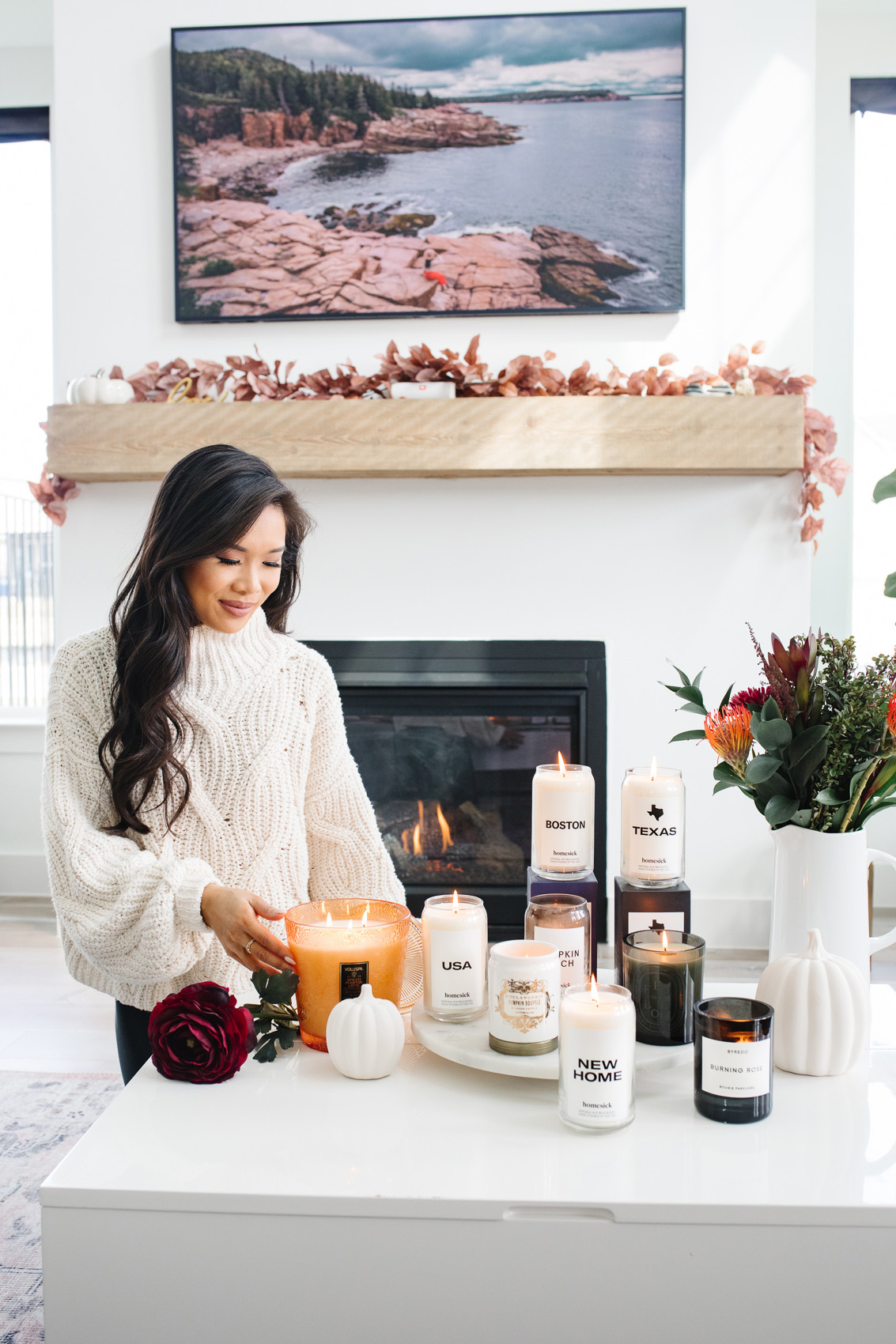 Blogger Hoang-Kim wearing a free people sweater with a variety of candles for her home