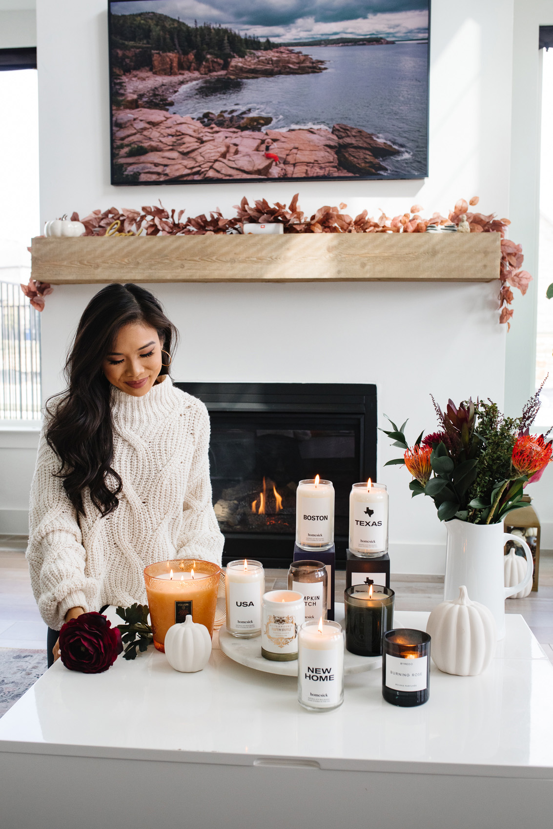 Blogger Hoang-Kim sharing her favorite luxury candles in front of her fireplace with Homesick candles, Voluspa spiced pumpkin latte, Diptyque feu de bois and more
