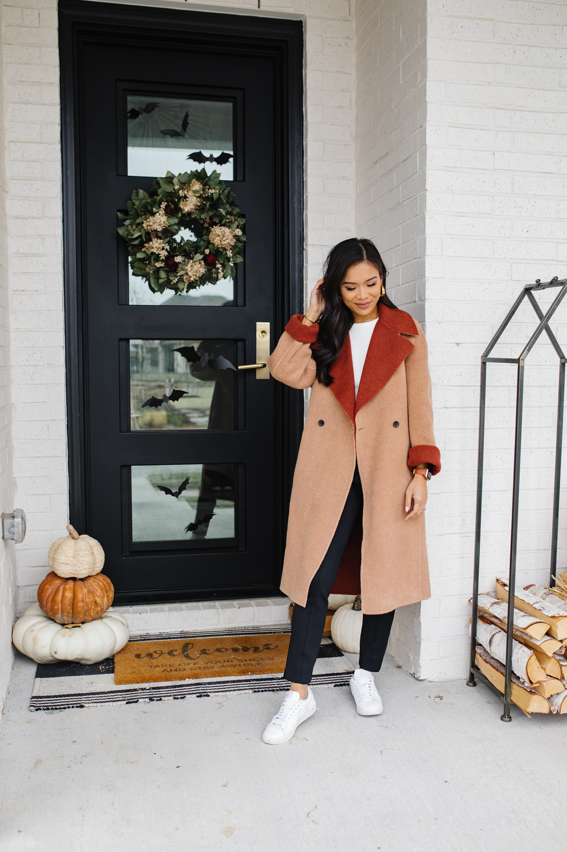 Blogger Hoang-Kim wears a reversible wool coat by M.M.LaFleur as a casual fall outfit with black pants, a white top and white sneakers