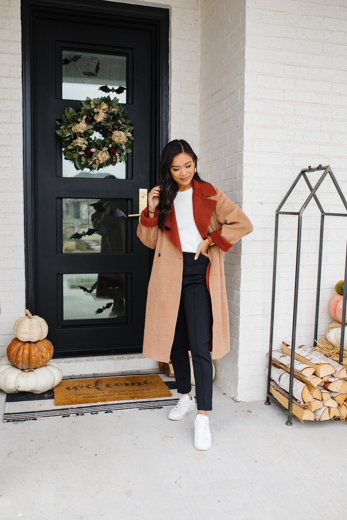 Hoang-Kim wearing a casual fall outfit with a reversible wool camel coat, white tee and black pants with white sneakers