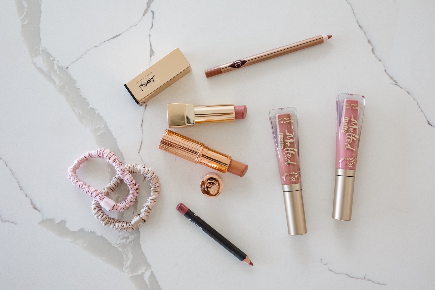 Nude pink lipsticks and liners including YSL Rouge Pur, Too Faced Melted Matte, Charlotte Tilbury Kissing Lipstick, Iconic Nude Liner on Calacutta foresta quartz countertop