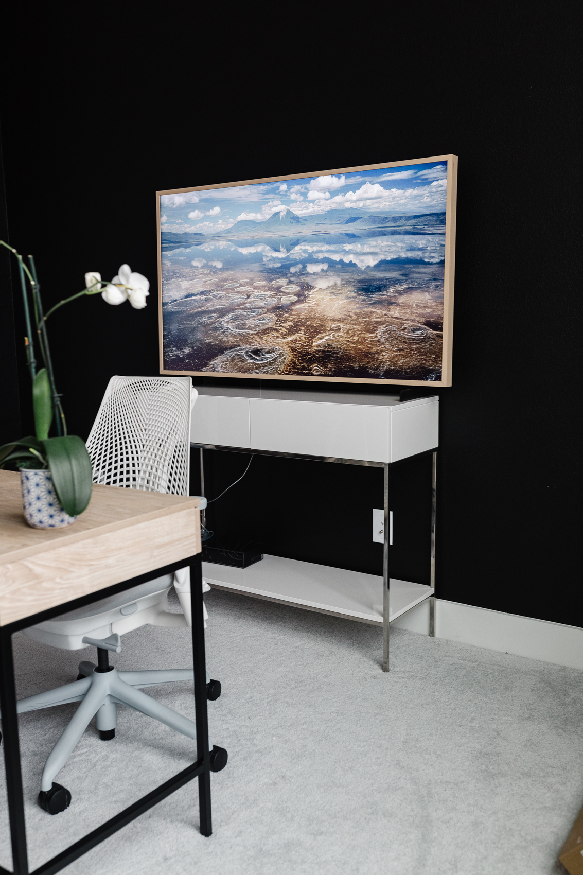 Samsung Frame 55" TV with a beige bezel in a home office painted Tricorn Black with a Herman Miller SAYL Chair