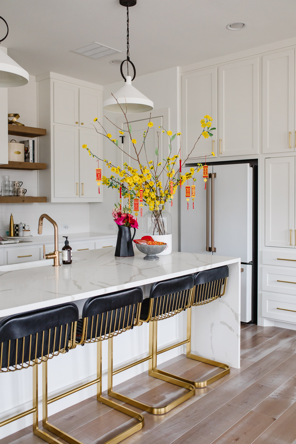 Ochna integerrima or hoa mai branches in a dipped vase with other Lunar New Year or Tet Vietnamese New Year decorations in a white kitchen in a transitional home