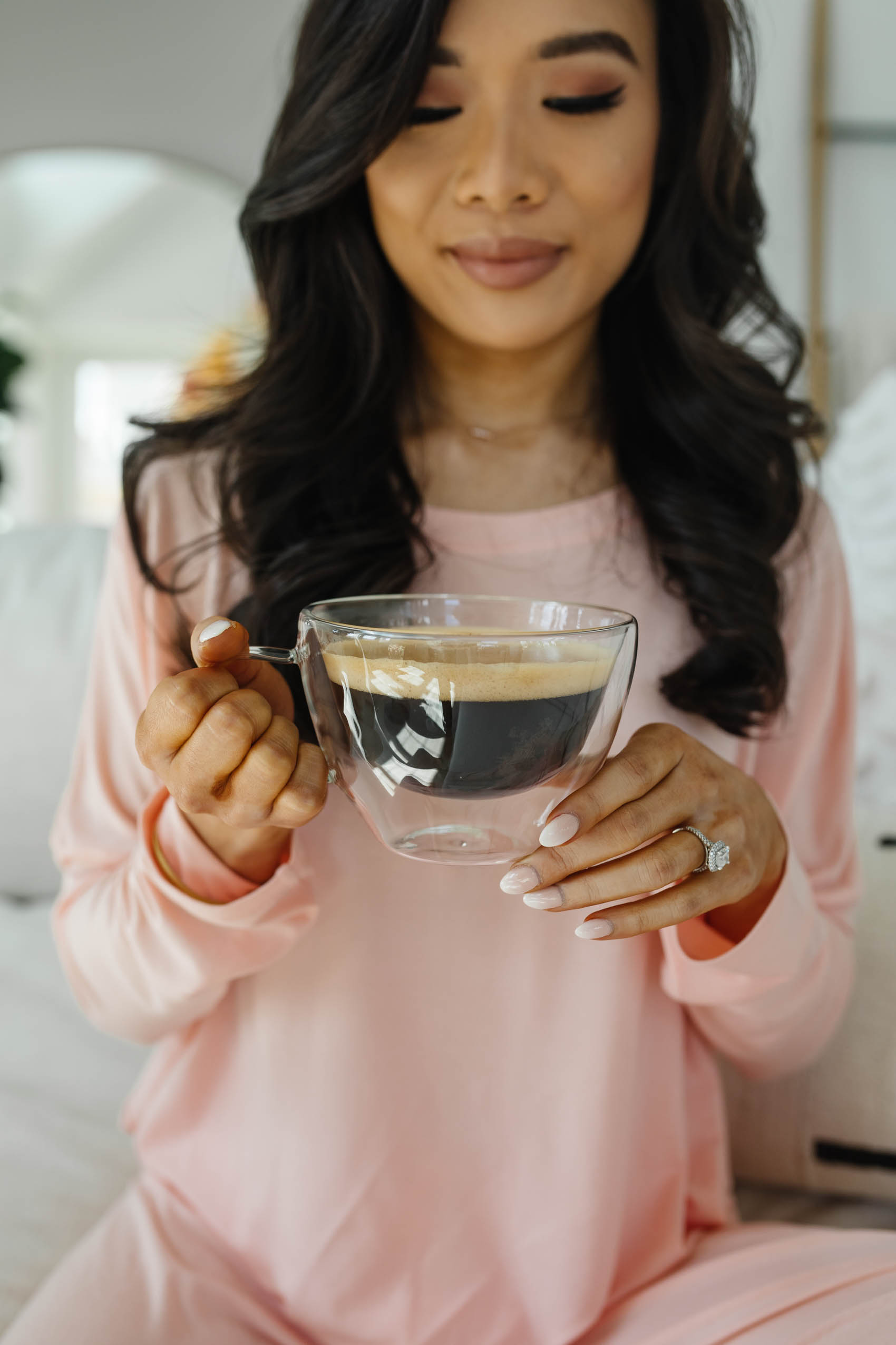 Asian woman holding a glass mug with coffee wearing an eberjey pj set