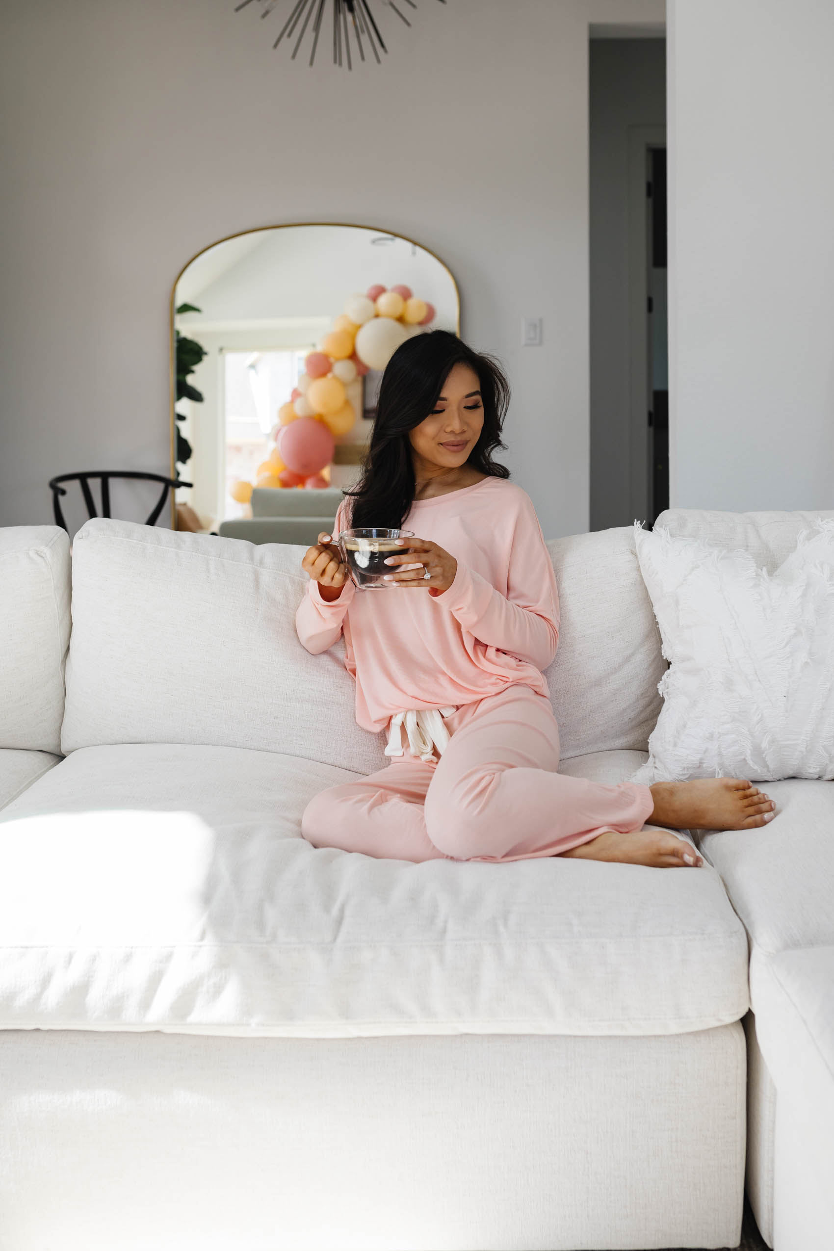 Blogger Hoang-Kim wears an eberjey pajama set while sitting on her Arhaus Beale sectional in her Dallas modern transitional home