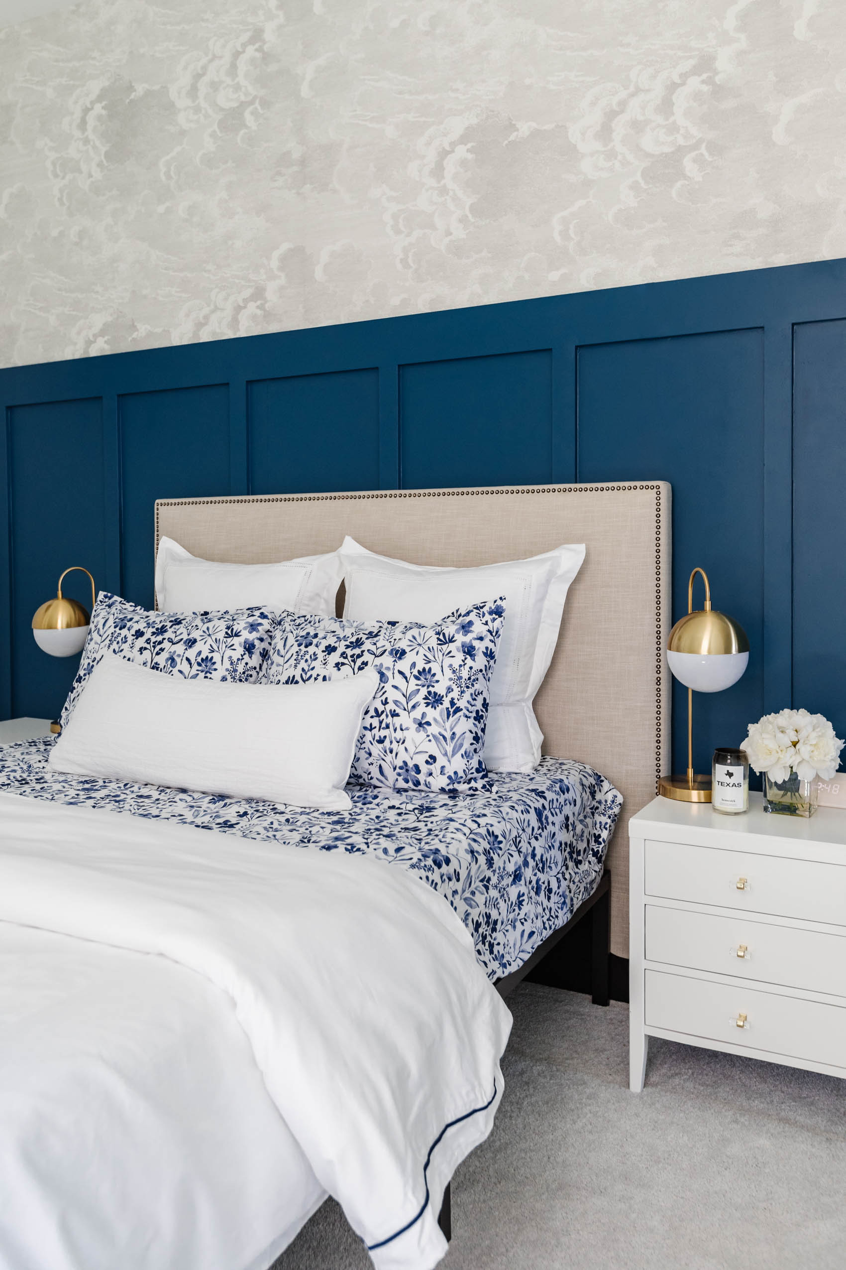 Guest room ideas with board and batten in PPG Chinese Porcelain with Cole & Son nuvolette wallpaper, west elm upholstered headboard, boll & branch botanical print bedsheets, white nightstands and brass table lamps