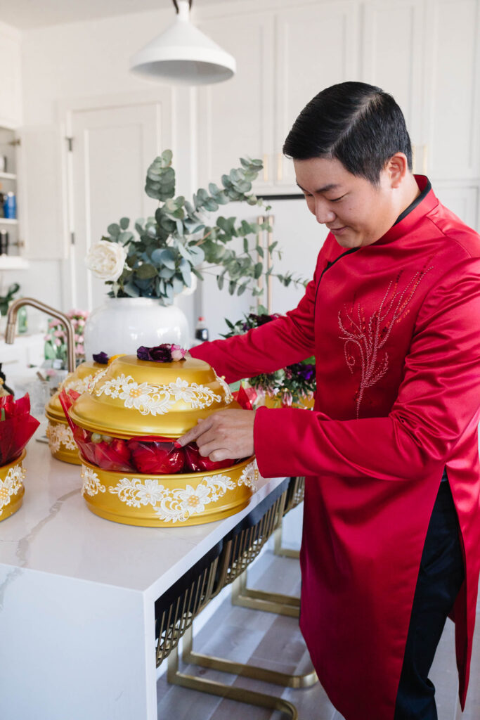 Johnny wearing a mens ao dai by Lahava preparing his mam qua for the Dam Hoi, a Vietnamese engagement party that's an important wedding tradition