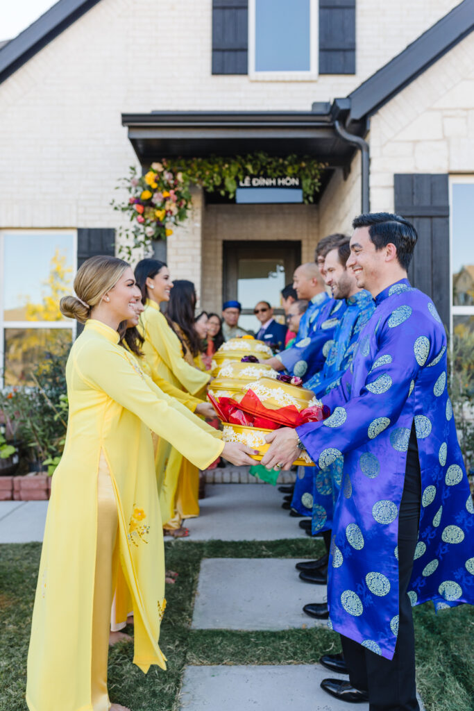 Bridesmaids and groomsmen wearing ao dai exchange mam qua at a Dam Hoi, a Vietnamese Engagement party, also known as a Le Dinh Hon, a Vietnamese wedding tradition