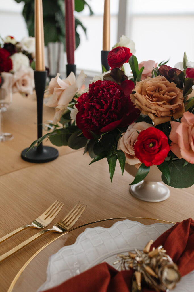 Thanksgiving table setting with a feminine touch for a Galsgiving. Floral arrangement from Something Pretty Floral with red peonies, toffee roses, red ranunculus and cream roses. 