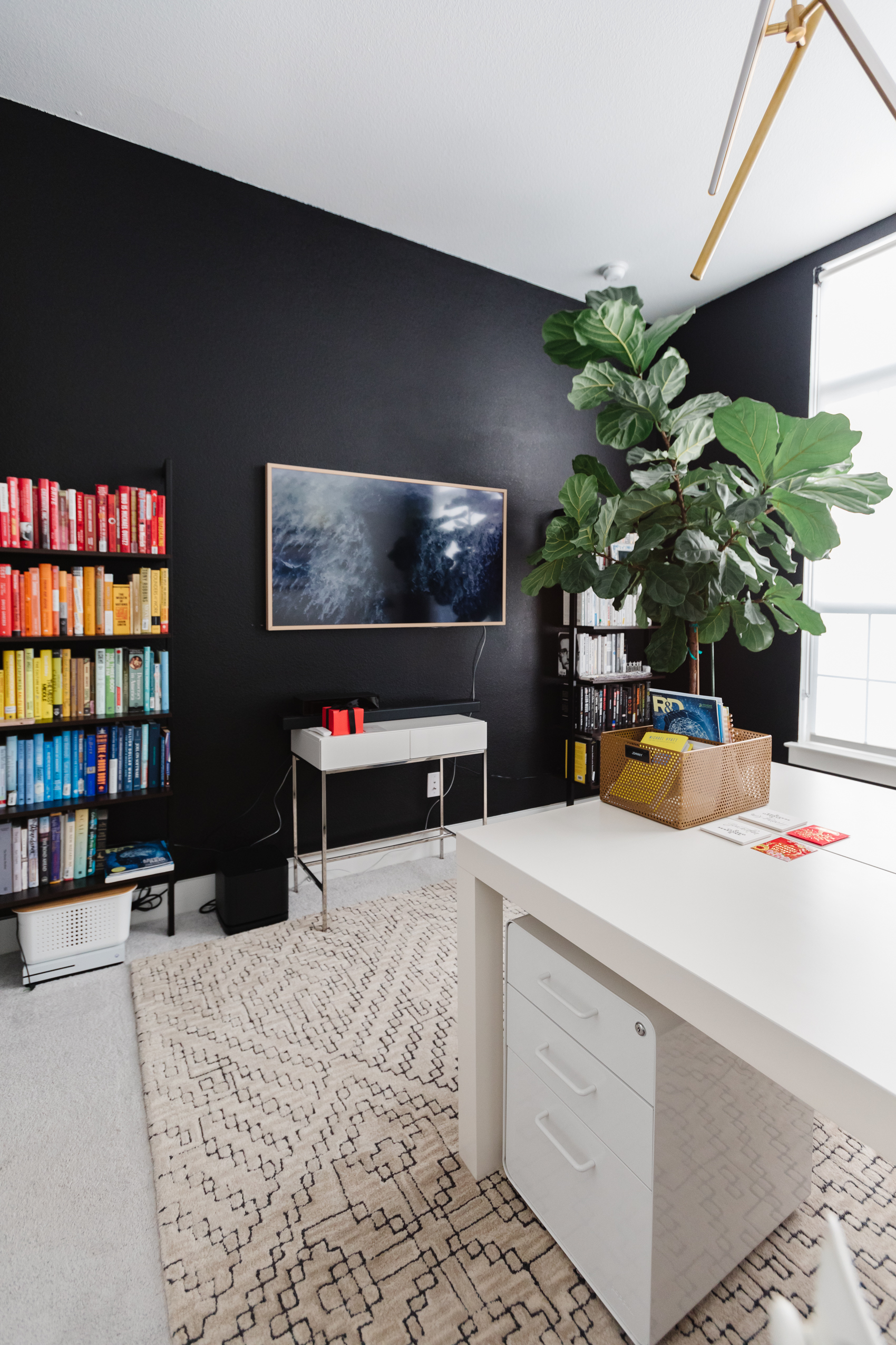 Blogger Hoang-Kim Cung discusses shared home office ideas in her transitional style home including a rainbow bookshelf with a black statement wall and samsung frame tv