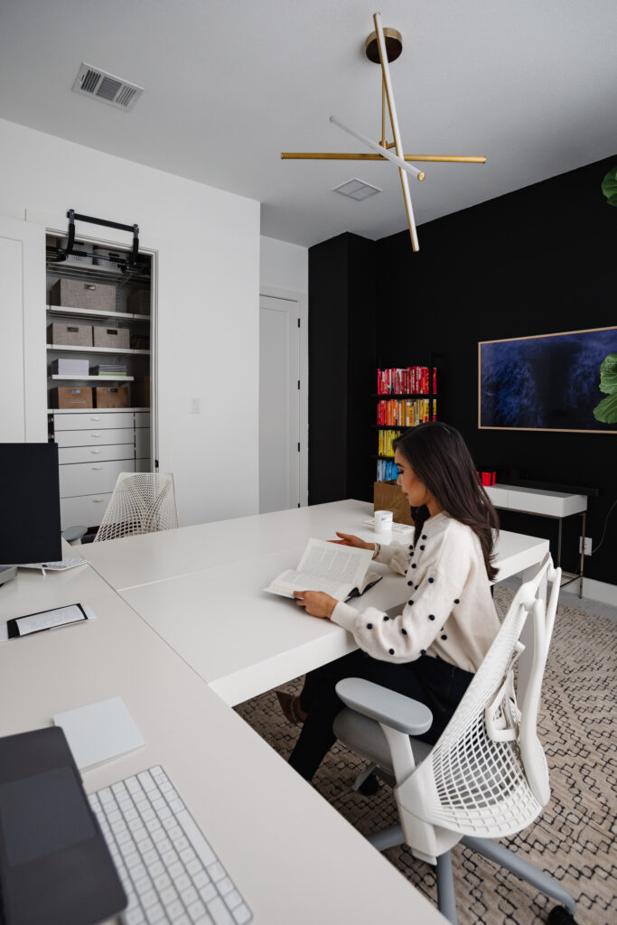 Blogger Hoang-Kim Cung discusses shared home office ideas in her transitional office including west elm parsons l-shaped desks, rainbow bookshelves, and a black statement wall