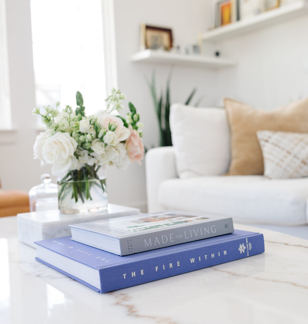 Blogger Hoang-Kim Cung's living room in her transitional style home with a marble coffee table, coffee table books, and flowers