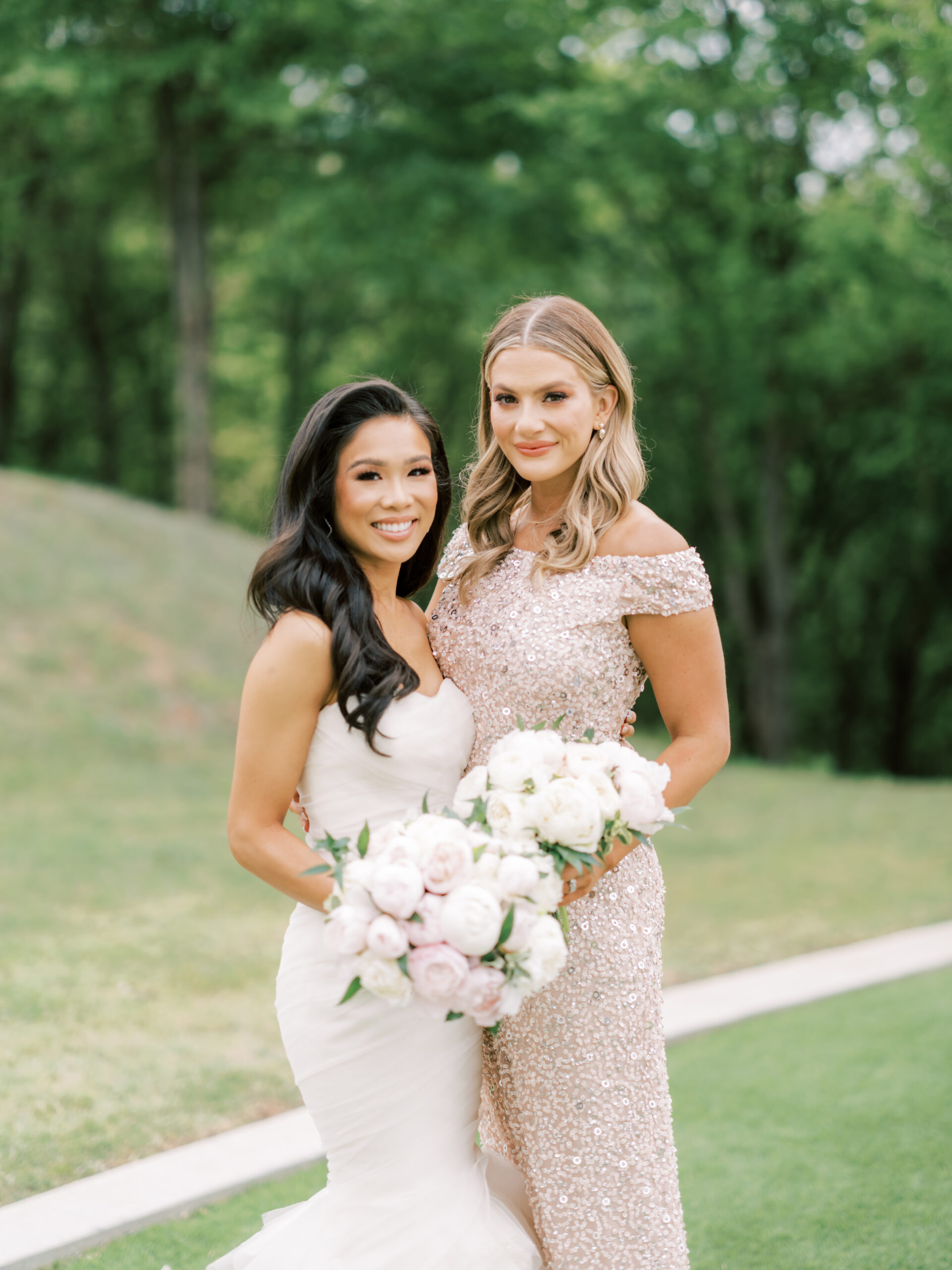 Hoang-Kim wearing a Vera Wang Gemma mermaid gown with her bridesmaid, Sarah Rose Summer wearing an Adriana Papell off-the-shoulder gown and olive + piper earrings