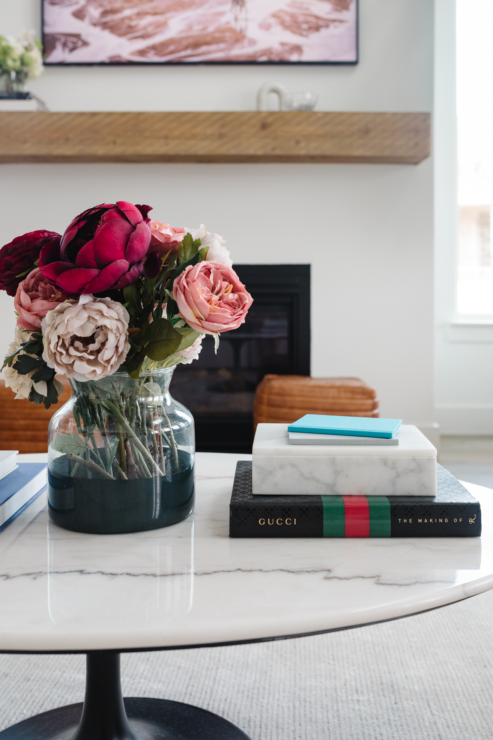 Faux floral arrangement in a navy McGee & Co vase, Gucci coffee table book, marble box to store knick knacks and more on an oval coffee table.