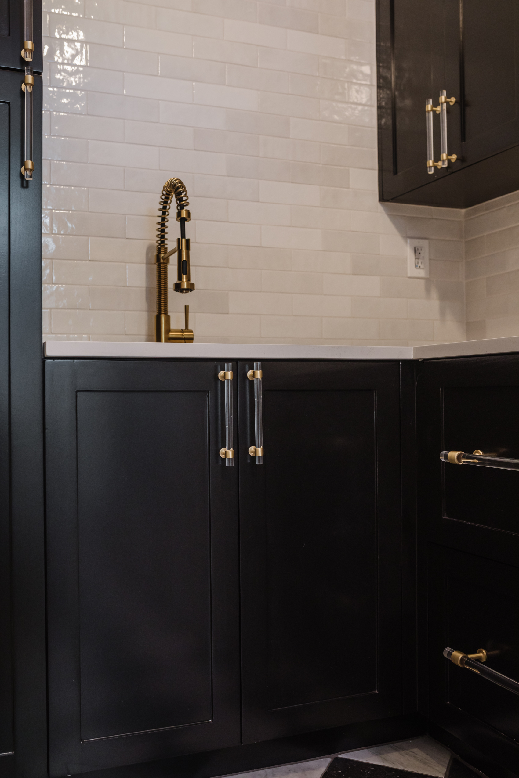 Custom cabinets painted Sherwin Williams Tricorn Black, brass pull down faucet, signature hardware acrylic and brass drawer pulls.