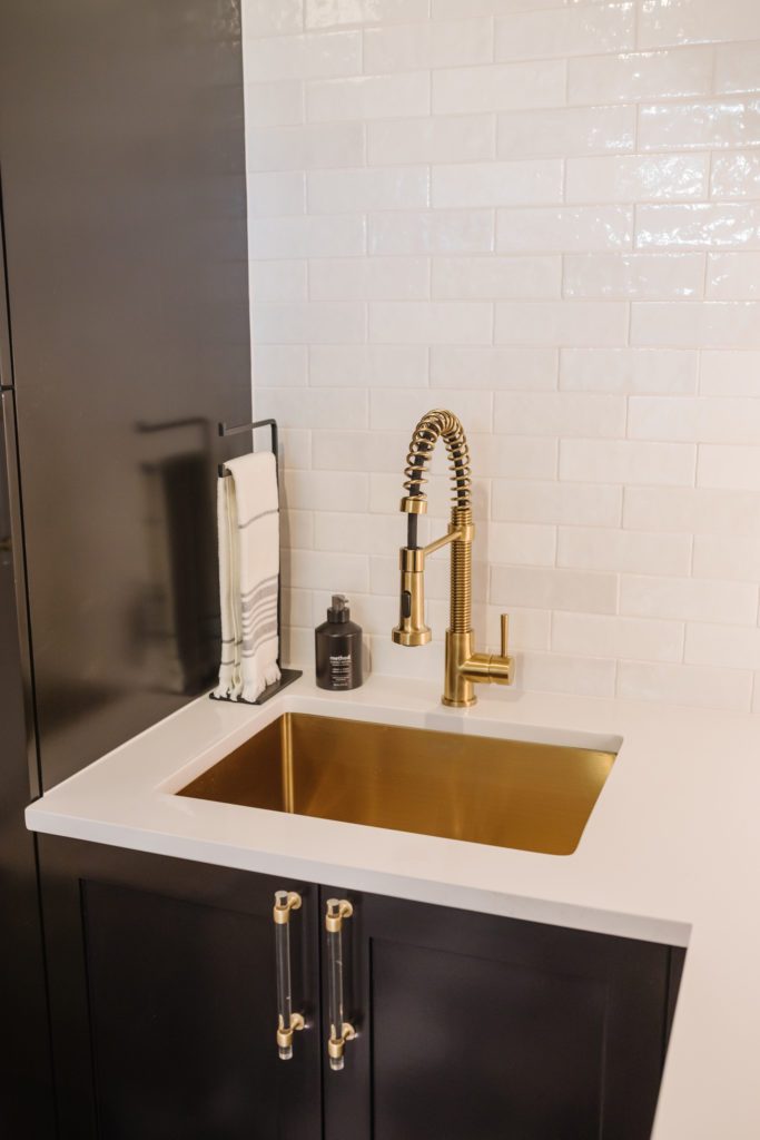 Custom cabinets painted Sherwin Williams Tricorn Black, brass pull down faucet, signature hardware acrylic and brass drawer pulls, Target towel stand.