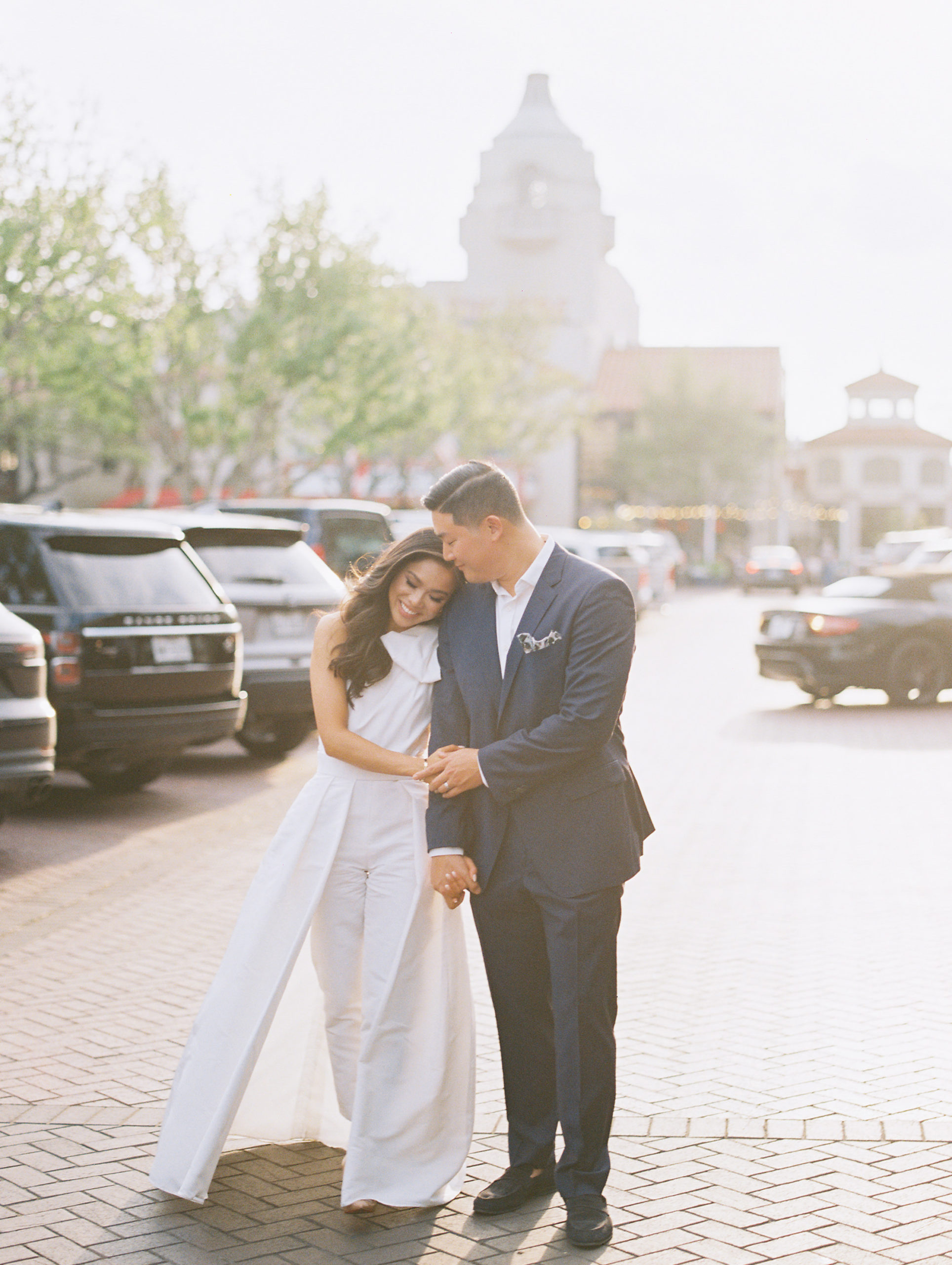 Blogger Hoang-Kim and her fiance Johnny in rehearsal dinner outfits wearing an Alexia Maria Blair Convertible Jumpsuit in white and Hugo Boss Genius Fit suit in navy at Highland Park Village in Dallas