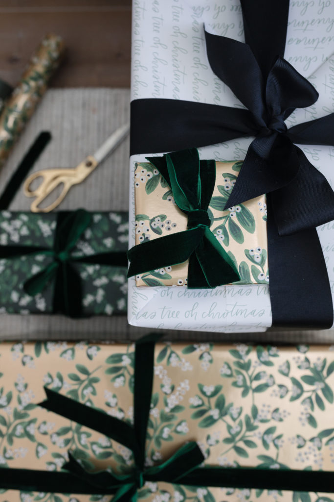 blogger hoang-kim cung shares how to wrap a gift with evergreen mistletoe wrapping sheets by rifle paper co, mistletoe gold wrapping sheets by rifle paper co, and oh christmas tree gift wrap by sugar paper + target