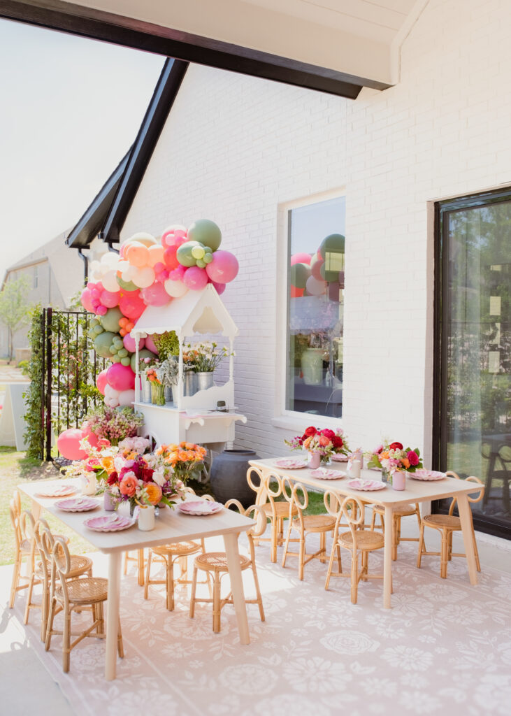 Floral first birthday party at blogger, Hoang-Kim's home with kids bow wicker chairs, kids tables, ruggable floral rug, DIY flower arrangement cart and florals from Something Pretty Floral