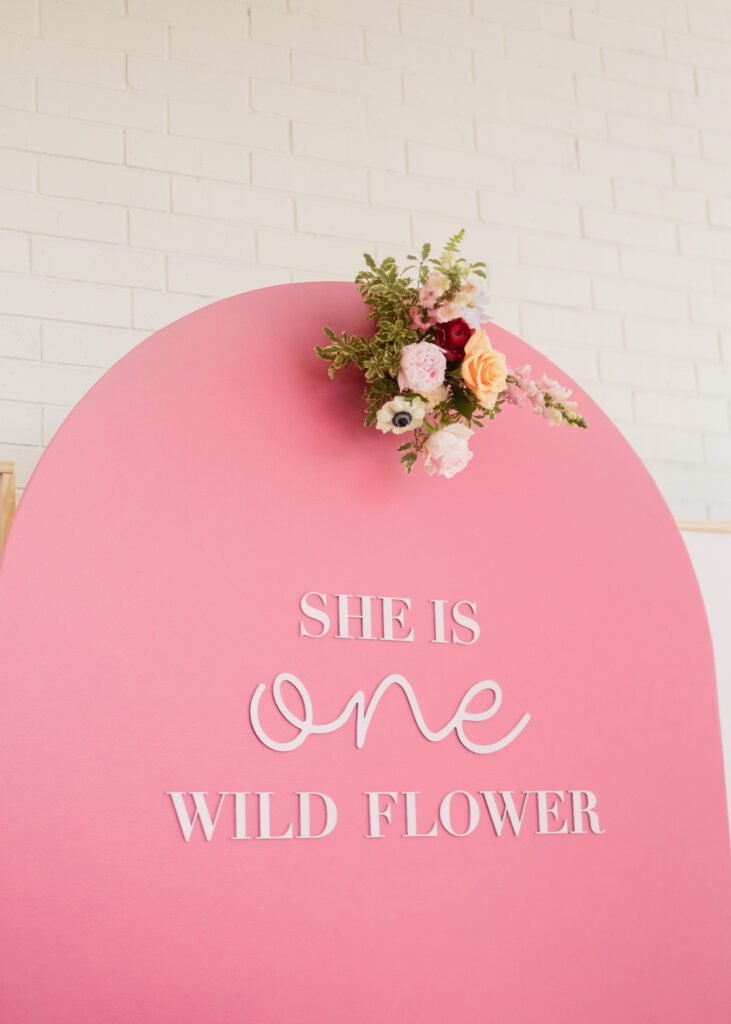 She is one wild flower party backdrop by Glo Party Co with wood lettering and a floral cluster from Something Pretty Floral